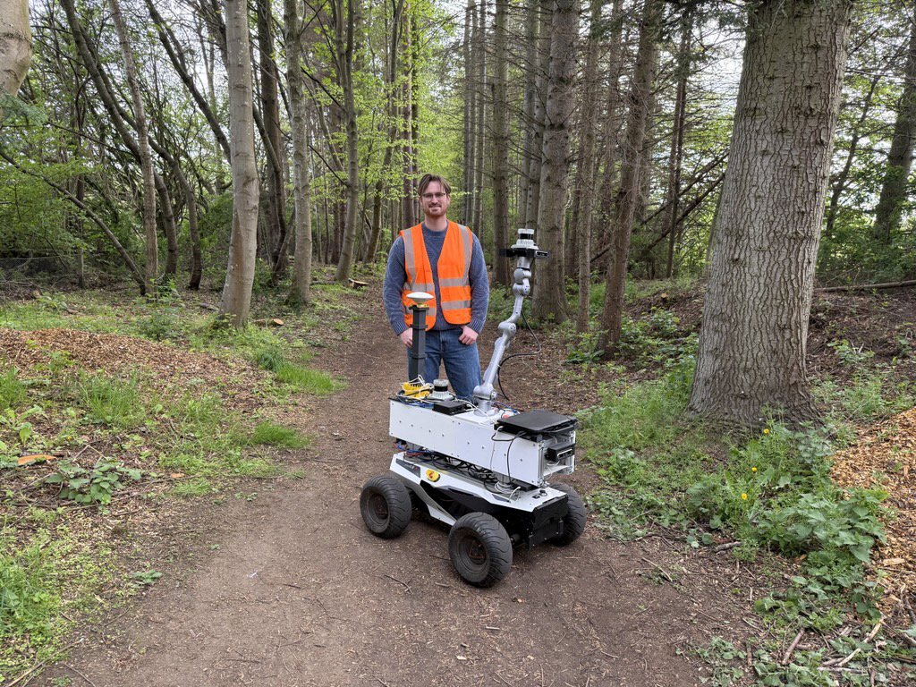 Ciaran Johnson with a field robot on a woodland path