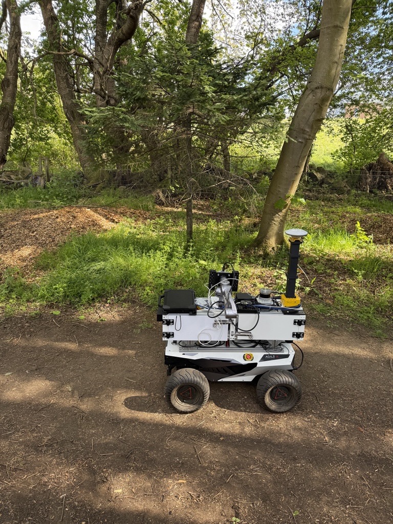 ALFRED positioned on the woodland trail at the start of a traversal, with the start tree and leaf-on canopy behind it